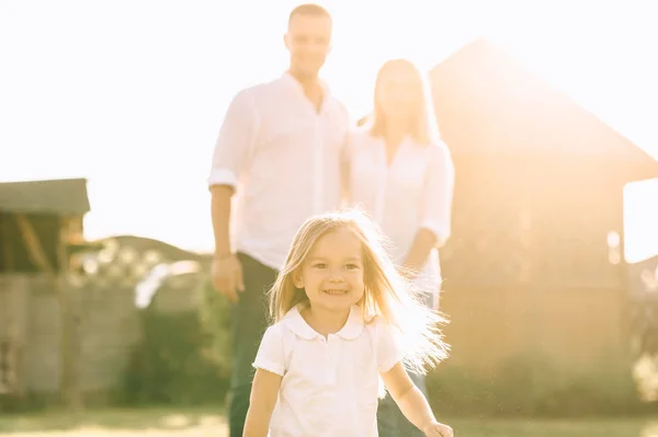 Selective focus of little kid running while parents standing behind on backyard — Stock Photo