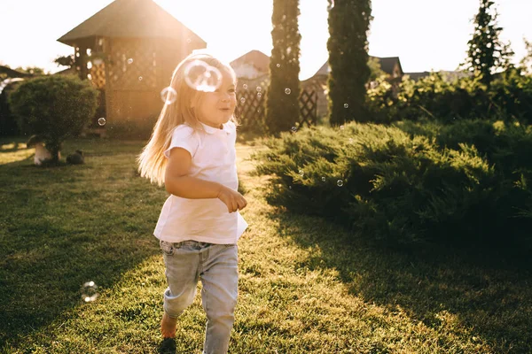 Little kid having fun with soap bubbles on backyard — Stock Photo