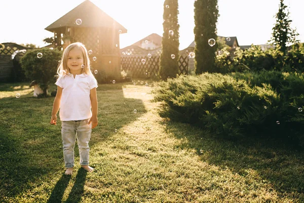 Bonito pouco loira criança olhando para a câmera enquanto em pé no quintal — Fotografia de Stock