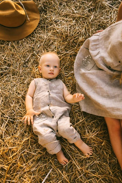 Overhead view of mother and son in linen clothing resting on hay together — Stock Photo