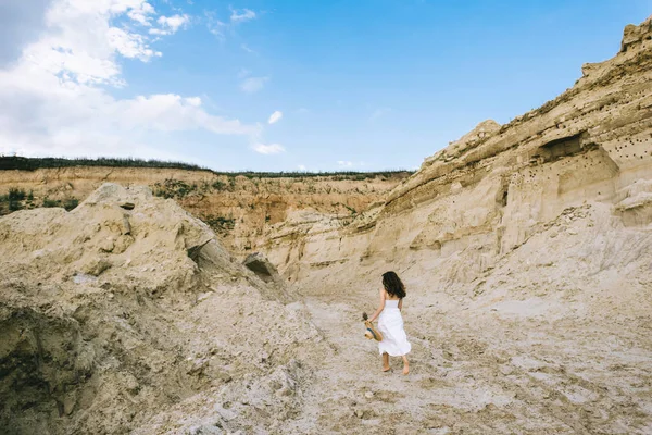 Rückansicht eines Mädchens im weißen Kleid, das in einer Sandschlucht mit blauem Himmel spaziert — Stockfoto