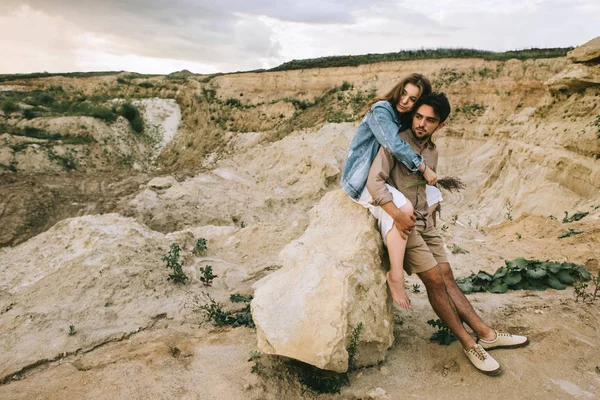 Giovane bella coppia che abbraccia e si siede sulla roccia nel canyon — Foto stock