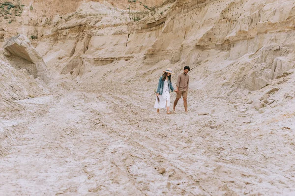 Bella coppia che si tiene per mano e cammina nel canyon di sabbia — Foto stock