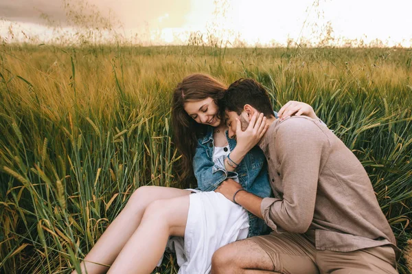 Happy stylish couple sitting on green grass on meadow — Stock Photo