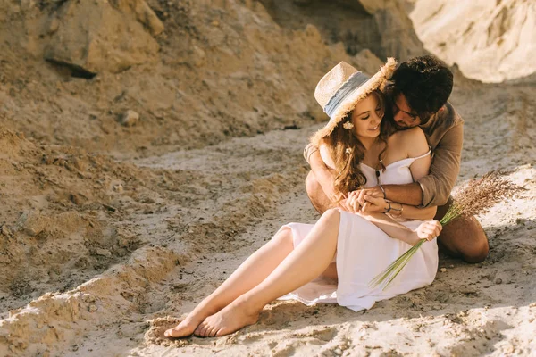 Улыбающаяся молодая пара, обнимающаяся в песчаном каньоне — стоковое фото