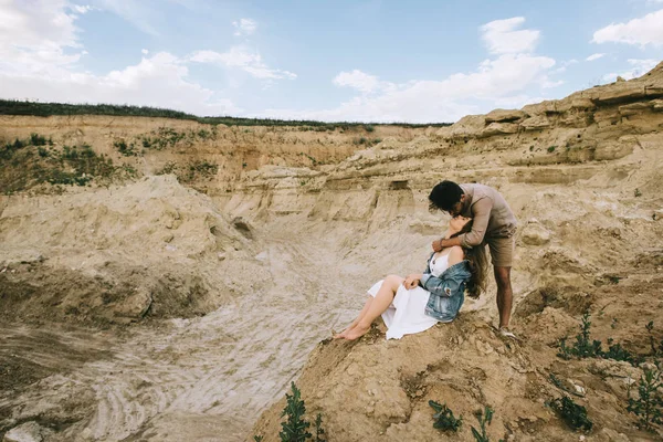 Homem elegante abraçando e beijando namorada no desfiladeiro de areia — Fotografia de Stock