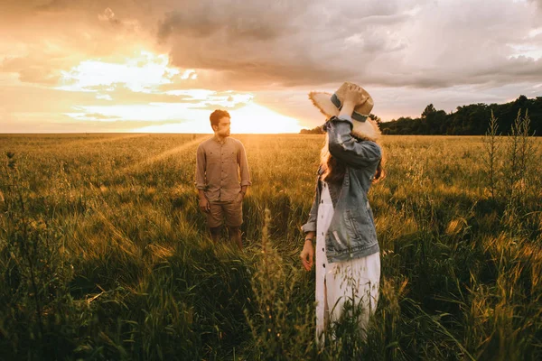 Beautiful couple walking on meadow at sunset with back light — Stock Photo