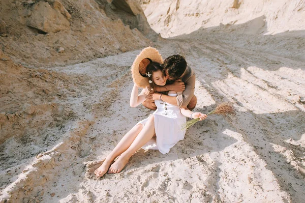 Beautiful happy couple embracing and sitting in sand canyon — Stock Photo