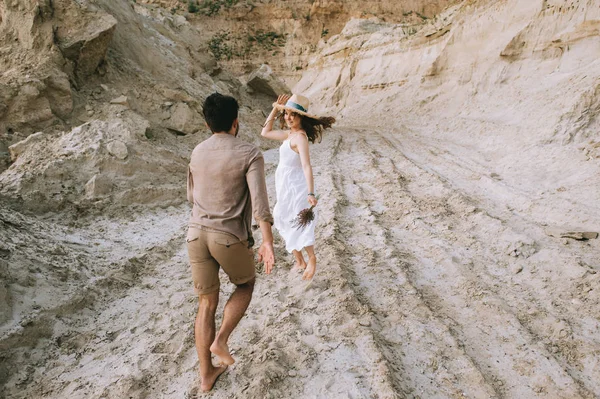 Beautiful happy couple running in sand canyon, love story — Stock Photo