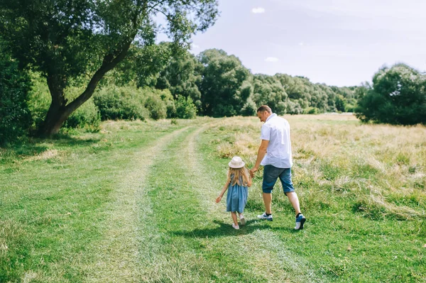 Back view of father holding hands with daughter and walking in field — Stock Photo