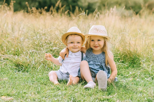 Adorable feliz rubia niños sentado en campo - foto de stock