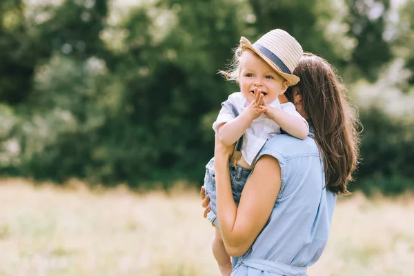 Mãe segurando filho a mãos e andando em campo — Fotografia de Stock