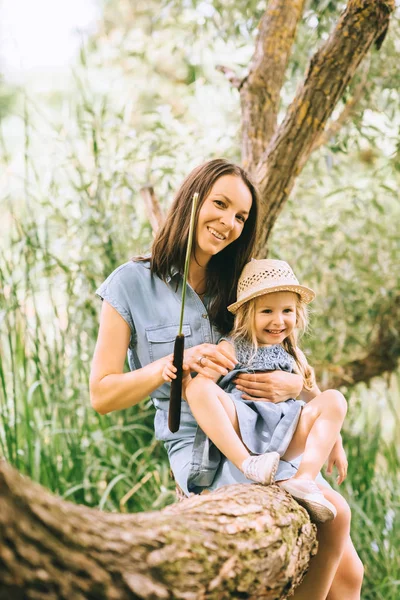 Schöne Mutter und lächelnde Tochter verbringen Zeit zusammen auf dem Baum — Stockfoto