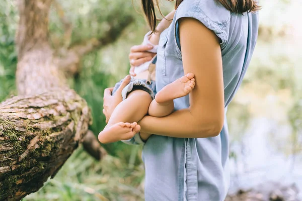 Vista ritagliata della madre che tiene piccolo bambino sulle mani — Foto stock