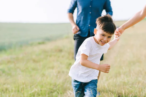 Imagen recortada de los padres y el hijo corriendo en el campo - foto de stock