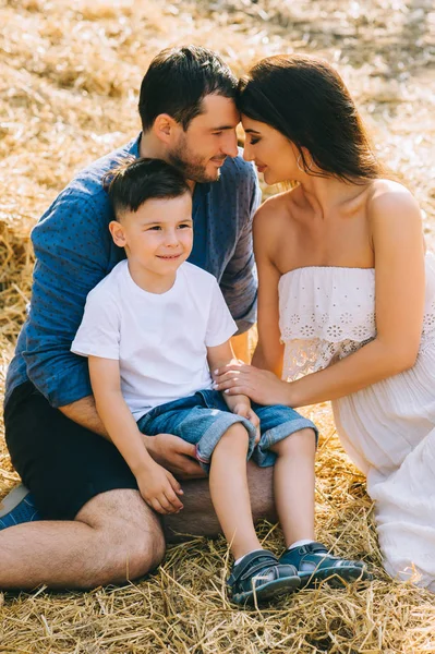 Genitori e figlio seduti sul fieno in fattoria — Foto stock