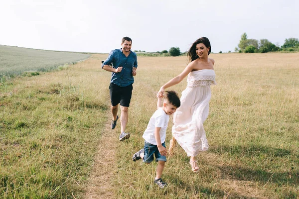 Glückliche Eltern und Sohn laufen auf Feld — Stockfoto