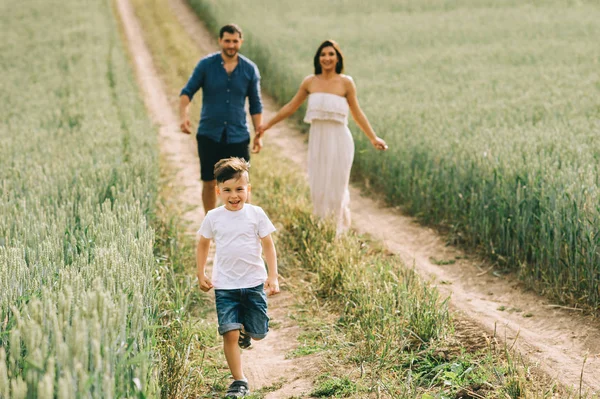 Pais felizes e filho correndo no caminho no campo — Fotografia de Stock