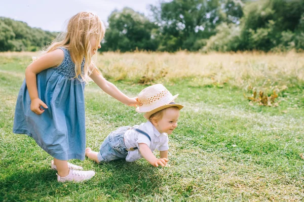 Adorables frères et sœurs blonds jouant dans le champ vert — Photo de stock