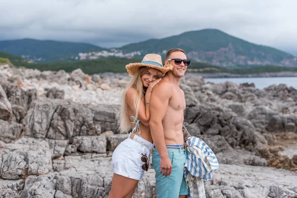 Novia sonriente tocando novio sin camisa en la playa de mar adriático en Montenegro - foto de stock