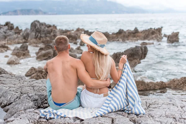 Rear view of girlfriend and boyfriend sitting on rocky beach of adriatic sea in Montenegro — Stock Photo