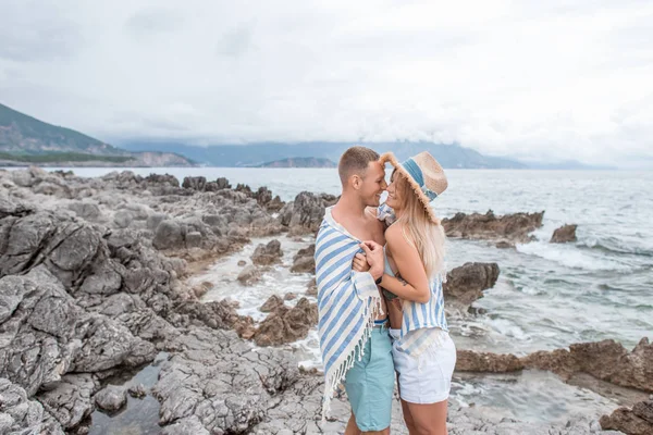 Vista lateral do belo casal jovem feliz no amor abraçando e sorrindo uns aos outros na praia rochosa em monten= — Fotografia de Stock