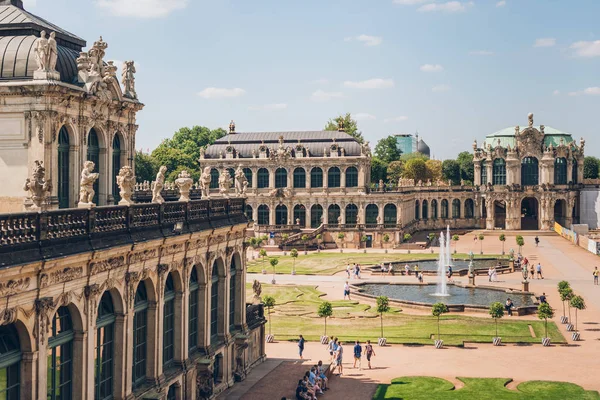 DRESDEN, ALEMANIA - 24 DE JULIO DE 2018: turistas caminando cerca de las fuentes y la hermosa arquitectura del antiguo palacio de Zwinger en Dresde, Alemania — Stock Photo