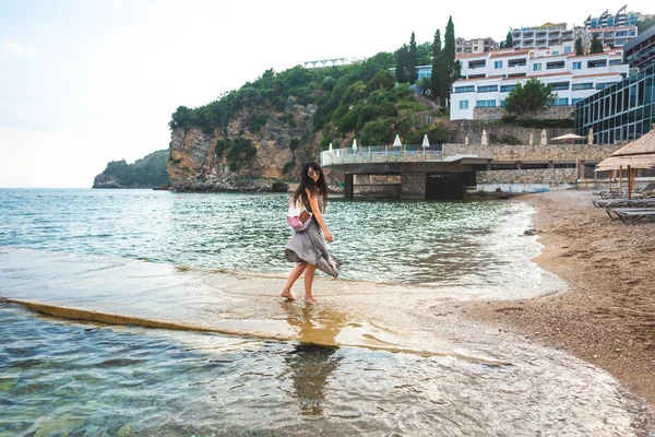 Mujer caminando desde el muelle a la playa de ricardova glava en Budva, Montenegro - foto de stock