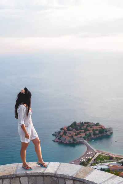 Vista lateral de la mujer mirando a la isla de Sveti Stefan con hotel resort en el mar Adriático, Budva, Montenegro — Stock Photo