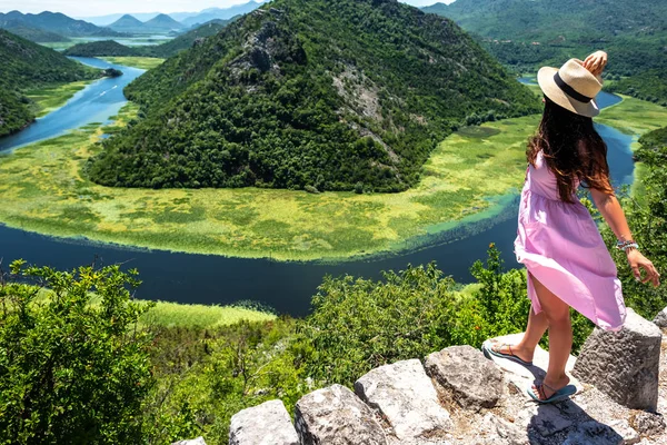 Vista de ángulo alto de la mujer en vestido rosa y sombrero de pie cerca del río Crnojevica en Montenegro - foto de stock