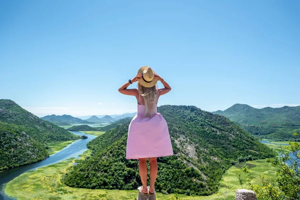 Заднього виду жінці в рожевій сукні стоячи на камінь з точки зору недалеко від річки Crnojevica в Чорногорії — стокове фото