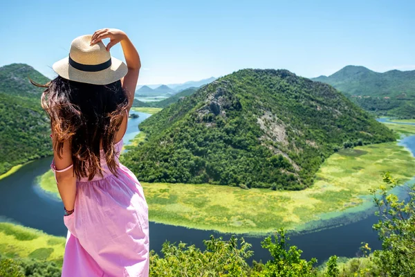 Back view of woman in pink dress touching hat near Crnojevica River (Rijeka Crnojevica) in Montenegro — Stock Photo