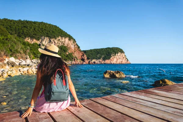 Vue arrière de la femme avec sac à dos assis sur le pont près de la mer à Budva, Monténégro — Photo de stock