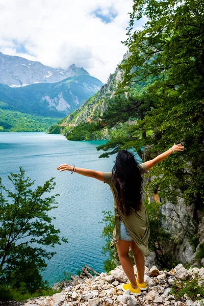 Vista posteriore della donna in piedi a braccia aperte vicino al lago Piva (Pivsko Jezero) in Montenegro — Foto stock