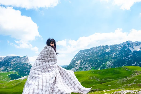 Hermosa mujer en manta caminando por el valle cerca de las montañas en el macizo de Durmitor, Montenegro - foto de stock