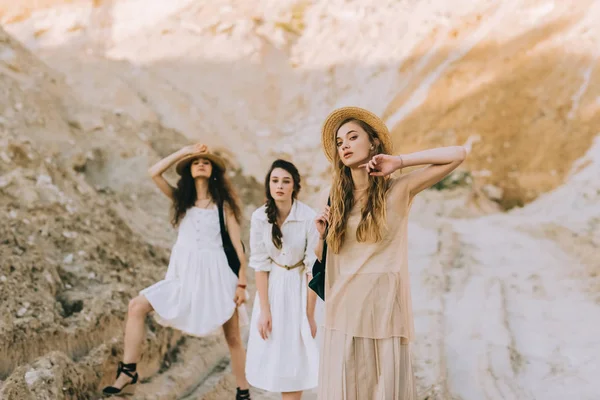 Pretty girls in trendy dresses and straw hats posing in sandy canyon — Stock Photo