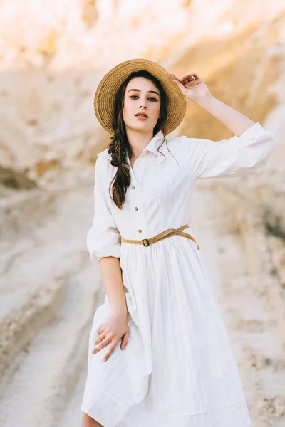 Encantadora menina elegante posando em vestido branco e chapéu de palha em canyon arenoso — Fotografia de Stock