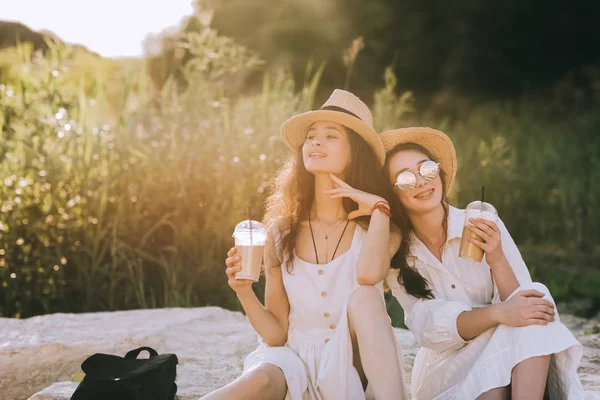 Beaux amis heureux avec des tasses de café latte assis sur le sol avec la lumière du soleil — Photo de stock