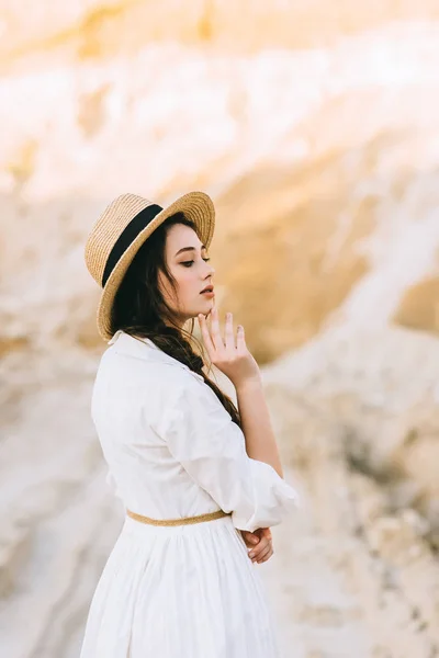 Привлекательная девушка позирует в модном платье и соломенной шляпе в песчаном каньоне — стоковое фото