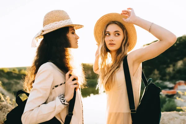 Привабливі подружки позують у солом'яних капелюхах біля ставка з підсвічуванням — стокове фото