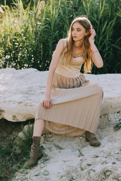 Attractive blonde girl in elegant dress sitting on ground — Stock Photo