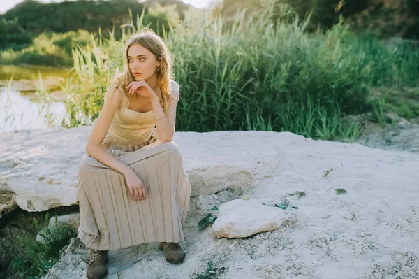 Красивая девушка, сидящая на земле возле озера — стоковое фото