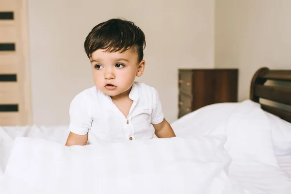 Nahaufnahme Porträt eines entzückenden kleinen Kindes, das auf dem Bett sitzt — Stockfoto