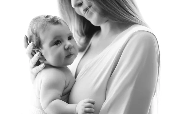 Vista parcial de la madre llevando al niño pequeño delante de las cortinas en casa, en blanco y negro - foto de stock
