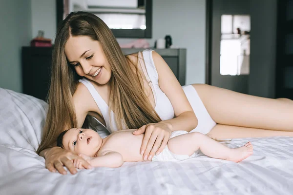 Selektiver Fokus einer lächelnden Mutter, die mit einem kleinen Jungen im Schlafzimmer im Bett liegt — Stockfoto