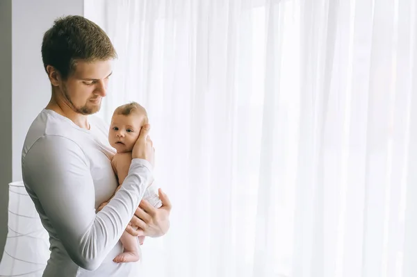 Seitenansicht des Vaters, der den kleinen Jungen zu Hause vor Vorhängen trägt — Stockfoto