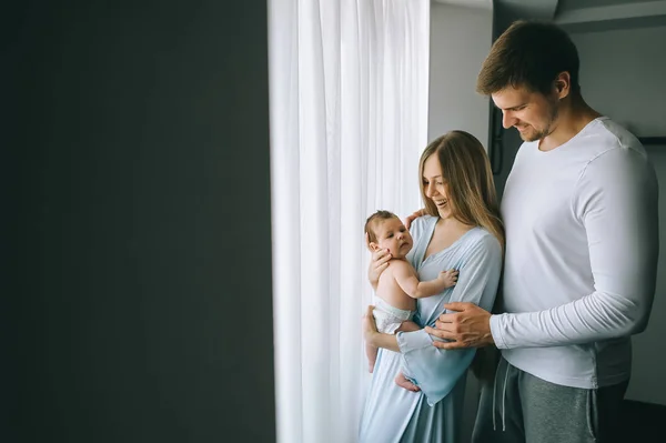 Enfoque selectivo de la familia feliz llevando niño pequeño delante de las cortinas en casa - foto de stock