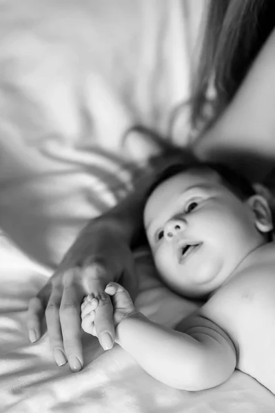 Noir et blanc photo de la mère tenant la main du petit garçon au lit à la maison — Photo de stock