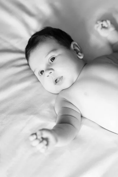 Чорно-білий портрет чарівного немовляти, що лежить в ліжку вдома — стокове фото