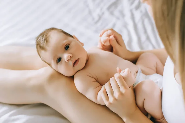 Vue partielle de la mère jouant avec adorable bébé garçon au lit à la maison — Photo de stock